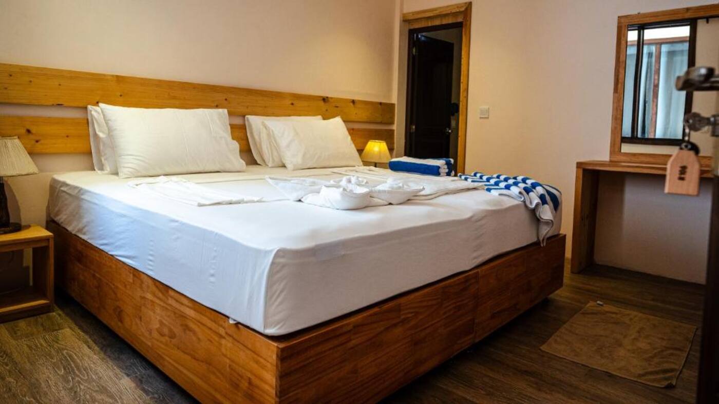 Wooden double bed with white linen in a guest room
